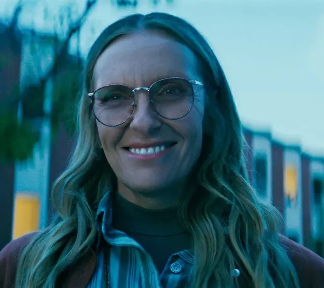 Uśmiechnięta Toni Collette w okularach, znana z wielu filmów i seriali, wygląda na zadowoloną.
