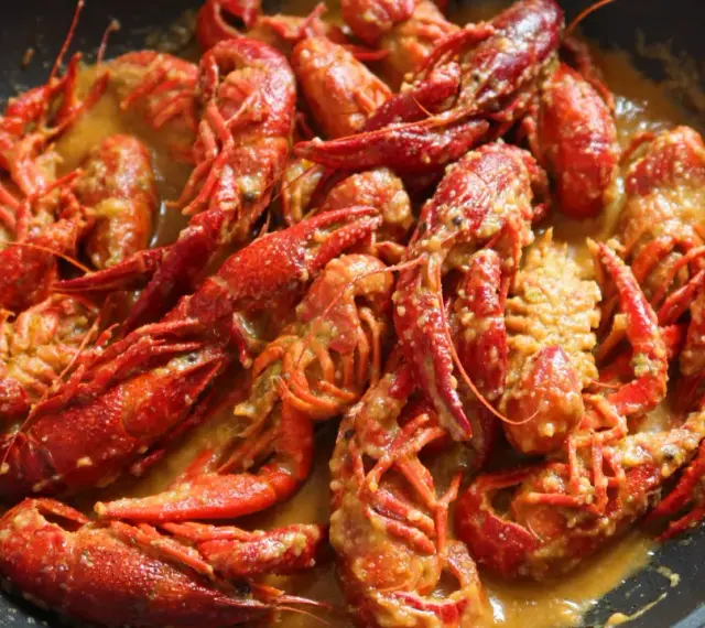 Un delicioso cangrejo de río en una sartén, bañado en una cremosa salsa. ¡Un manjar listo para disfrutar!