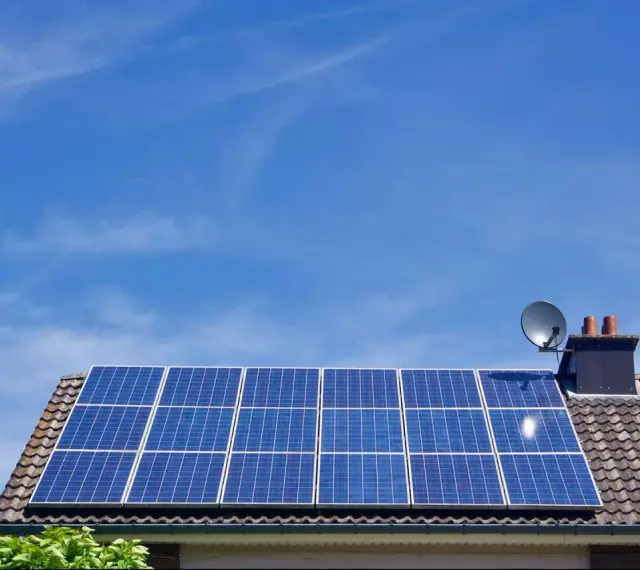 Panele fotowoltaiczne na dachu domu, symbolizujące długą żywotność i ekologiczne pozyskiwanie energii.
