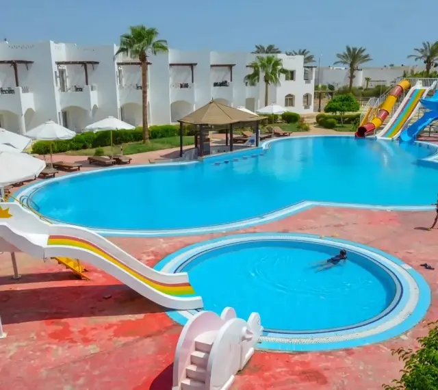 Egipt last minute all inclusive najtaniej: basen z wodnymi zjeżdżalniami i palmami, idealny na wakacje.