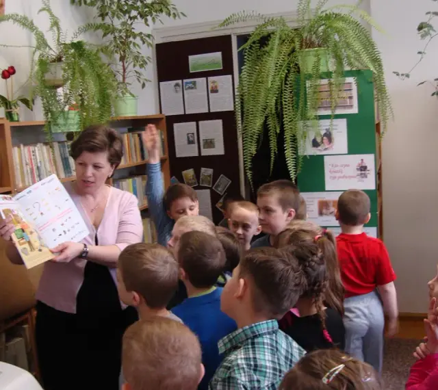 Nauczycielka czyta dzieciom książkę, tworząc inspirujące lekcje biblioteczne scenariusze. Dzieci słuchają z uwagą.