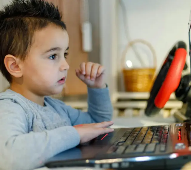 Chłopiec z zaciekawieniem ogląda na laptopie materiały o biologii dla dzieci.