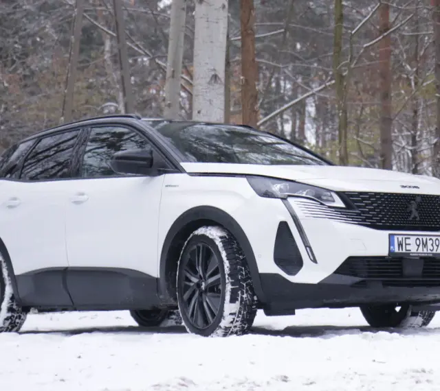 Biały Peugeot 3008 hybryda na śniegu, gotowy na zimowe przygody w lesie.