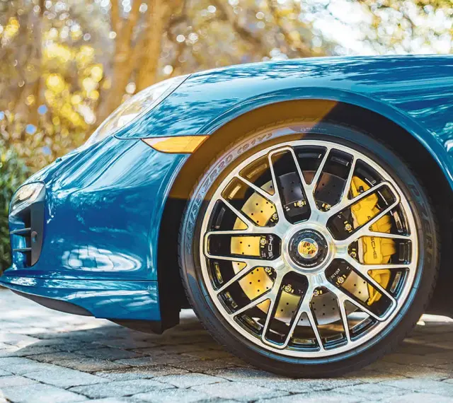 Błękitne Porsche z żółtymi zaciskami hamulcowymi i wieloramiennymi felgami. To jest et felgi, które dodają sportowego charakteru.