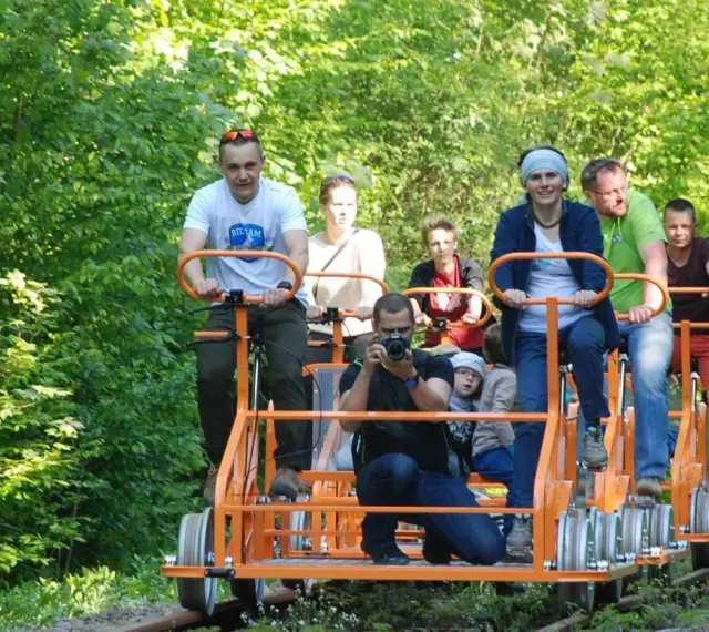 Rodzina na drezynach w Bieszczadach, ciesząca się zielenią i słońcem. Radość i wspólna przygoda na torach.