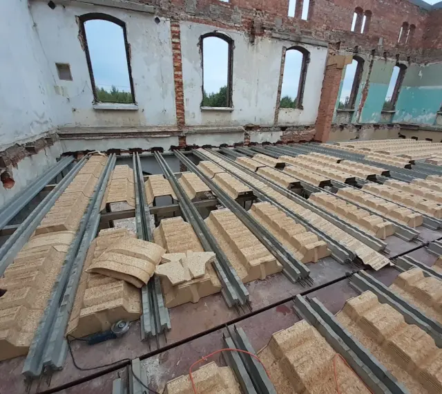 Rozpoczęła się wymiana stropu w starym domu. Metalowe belki i prefabrykowane elementy stropowe czekają na montaż.