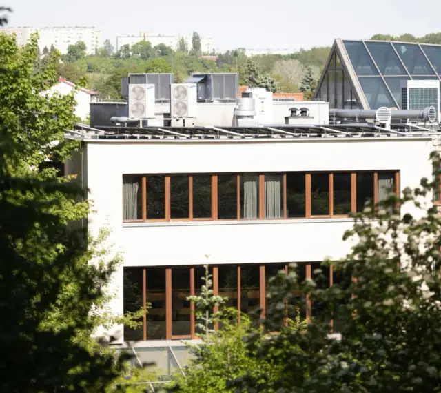 Nowe budynki od września 2026 będą musiały posiadać instalację fotowoltaiczną. Na dachu budynku widać panele i klimatyzatory.