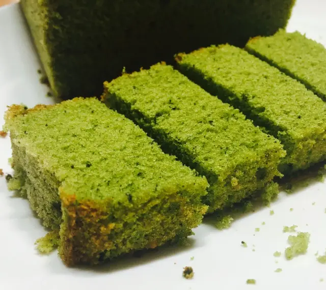 Puszyste ciasto matcha pokrojone w prostokątne kawałki, ułożone na białym talerzu.