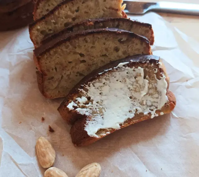 Pyszny chlebek bananowy z airfryera, pokrojony w kromki, jedna posmarowana masłem. Idealny na śniadanie.