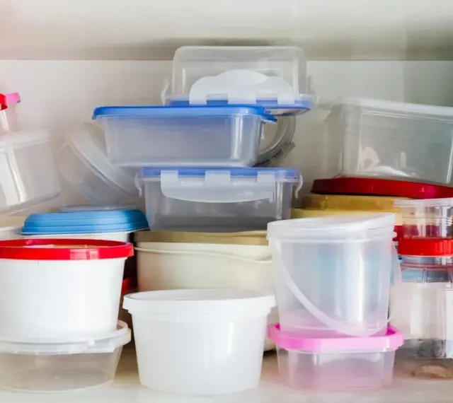 Stos pojemników na żywność, niektóre z kolorowymi pokrywkami. Uważaj na ftalany w plastiku.