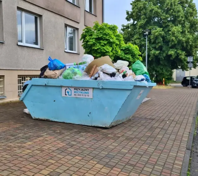 Kontener na śmieci pełen worków i odpadów, z napisem "Przyjazny Recykling". Data: 16 02 14.