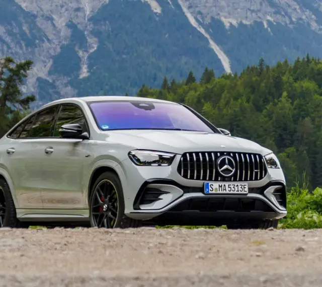 Biały Mercedes GLE 53 AMG coupe na tle górskiego krajobrazu z lasem.