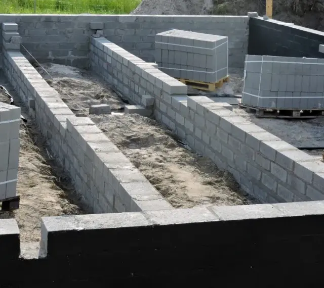Budowa fundamentów z bloczków betonowych, przygotowanie pod izolację pionową fundamentów.