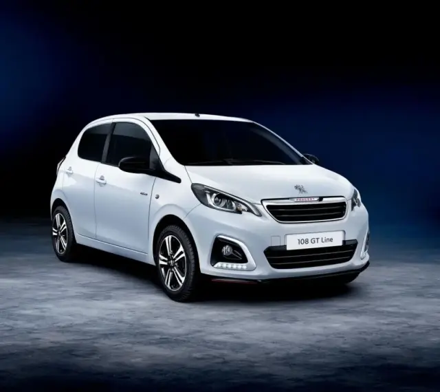 Biały Peugeot 108 GT Line stoi na ciemnym tle.