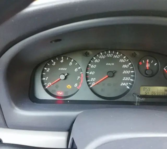 Migająca kontrolka samochodu z kluczykiem Nissan na desce rozdzielczej. Obok świeci się kontrolka oleju.