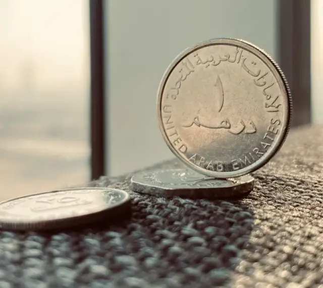 Monety z Zjednoczonych Emiratów Arabskich. Jedna z nich, z napisem "United Arab Emirates", stoi pionowo. To właśnie te monety symbolizują walutę AED, co to jest?