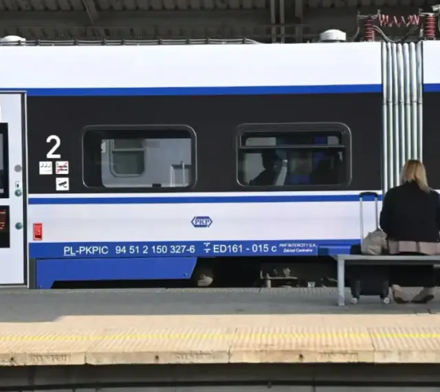 Kobieta z walizką czeka na pociąg PKP Intercity, szukając tanich biletów.