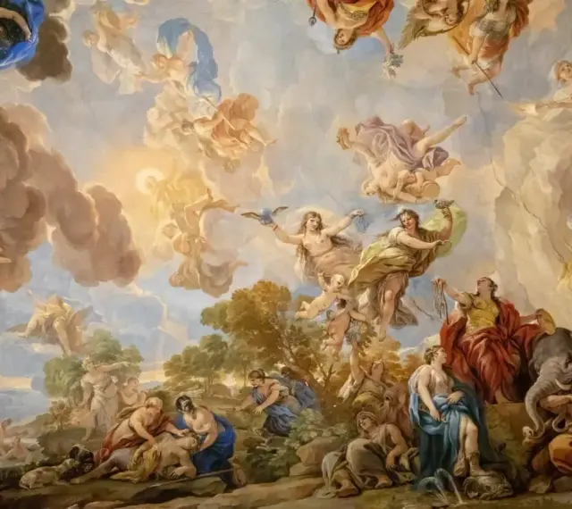 Barokowy fresk na suficie ukazuje niebiańską scenę z postaciami mitologicznymi, aniołami i chmurami, pełną dynamiki i przepychu.