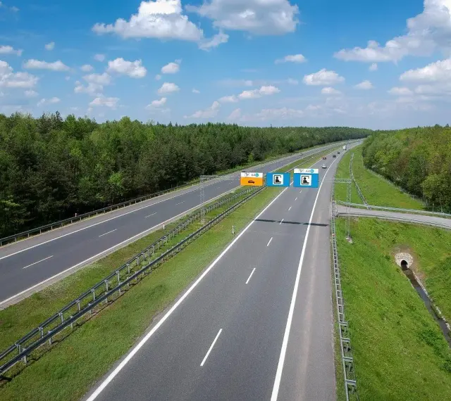 Znaki na autostradzie A4 informują, czy jest ona płatna. Widok na pustą autostradę w słoneczny dzień.