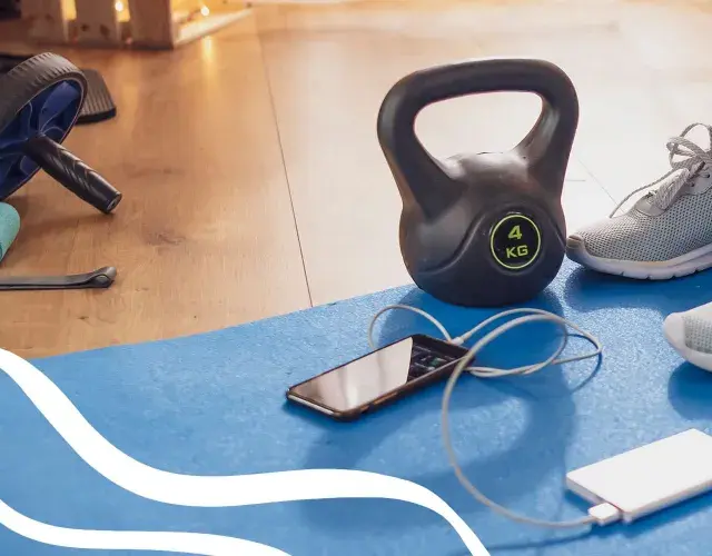 Gotowy na trening cardio? Kettlebell, gumy oporowe, rolka do ćwiczeń i telefon z powerbankiem czekają na matę.