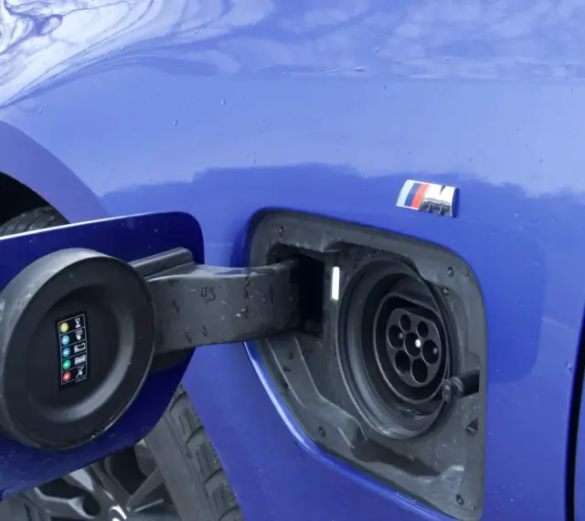 Niebieskie BMW 330e z otwartą klapką gniazda ładowania.