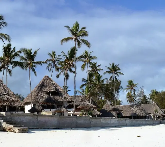 Rajskie plaże Zanzibaru, palmy i domki z krytymi strzechą dachami. Przed wyjazdem warto pomyśleć o zanzibar szczepienia.