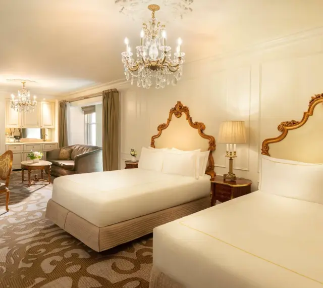Luksusowy pokój z dwoma łóżkami w hotelu Plaza w Nowym Jorku, z kryształowym żyrandolem i złotymi zdobieniami. Zastanawiasz się, ile kosztuje noc w hotelu Plaza w Nowym Jorku?