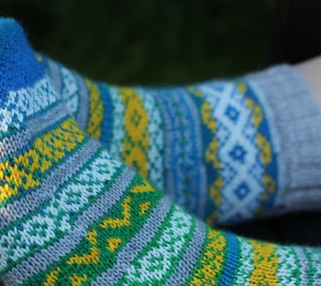 Två par stickade sockor med färgglatt sticka mönster med två färger i blått, gult, grönt och vitt.