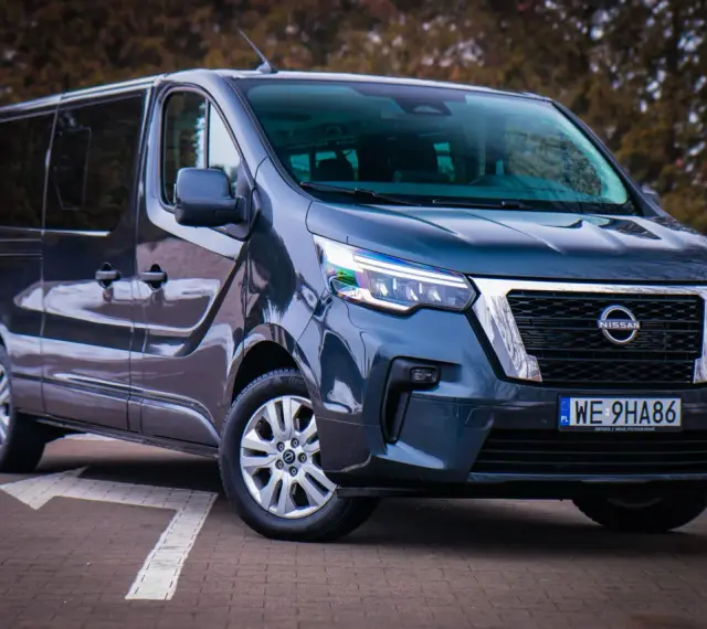 Ciemnoszary Nissan NV300 z nowoczesnymi światłami LED stoi na parkingu.