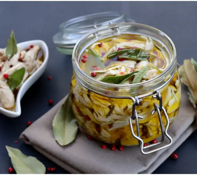 Un vasetto di antipasto piemontese di carne bianca sott'olio, con erbe aromatiche e pepe rosa. Accanto, una ciotolina con lo stesso saporito antipasto.