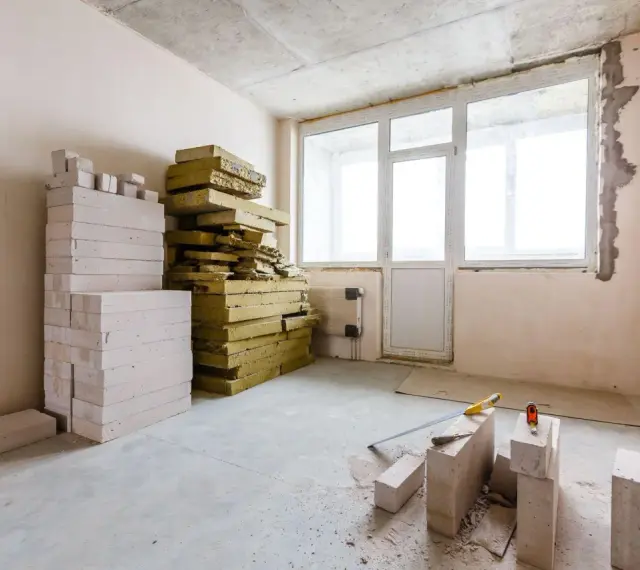 Materiały budowlane, w tym pustaki i wełna mineralna, czekają na **ocieplenie ścian od wewnątrz**.