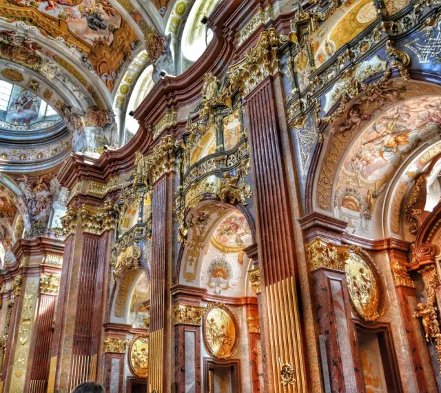 Bogata architektura baroku zachwyca złotymi zdobieniami, marmurowymi kolumnami i freskami na sklepieniach.