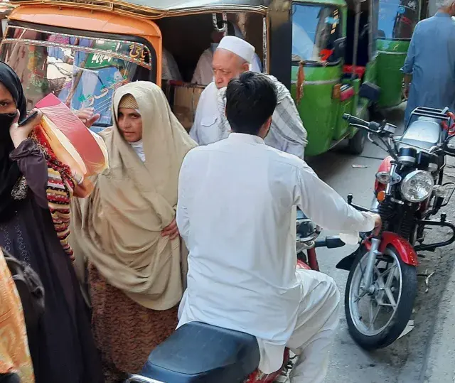 Ludzie na ulicy w Pakistanie, wśród nich kobiety w hidżabach i dzieci. Czy pakistan jest bezpieczny? Tłum na targu, ruchliwa ulica.