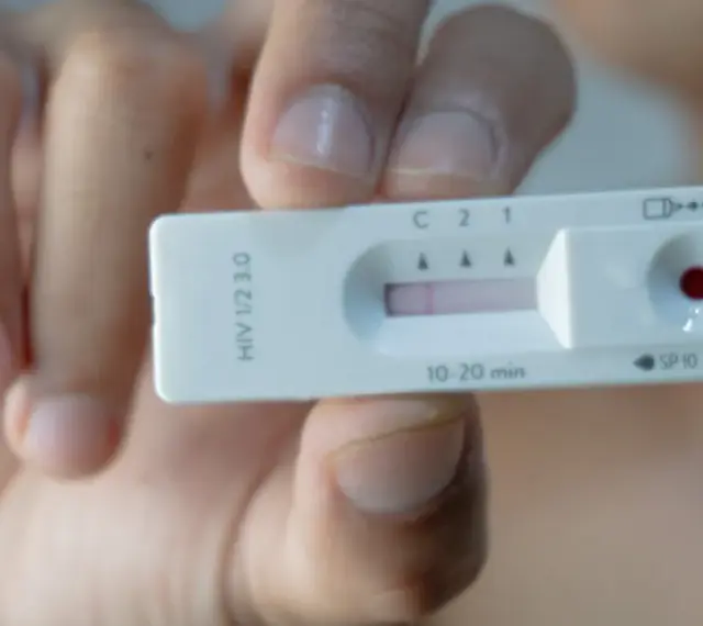 Dłoń trzyma test na HIV z widocznym wynikiem.