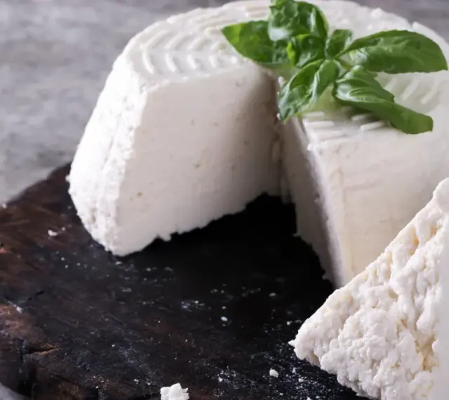 Świeża ricotta z bazylią na ciemnej desce. Idealna do lekkich posiłków, dbając o ricotta kcal.