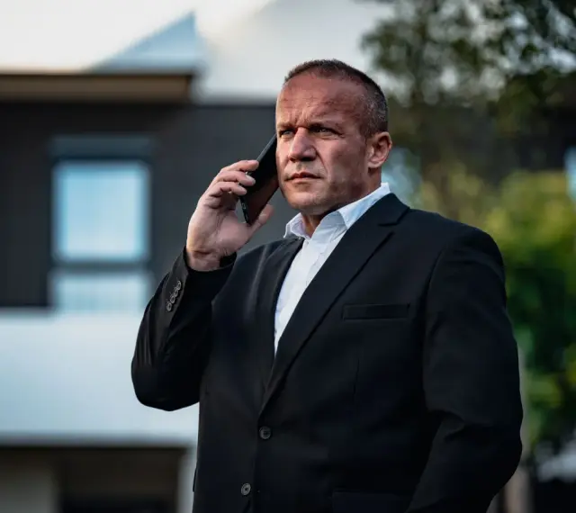 Krzysztof Bukowski, reżyser, w garniturze rozmawia przez telefon.