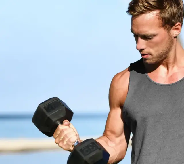 Mężczyzna ćwiczy biceps z hantlem. Zastanawia się, ile serii na klatę w tygodniu będzie optymalne dla jego treningu.