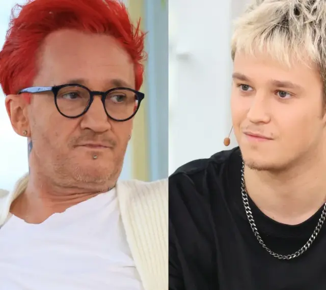 Xavier Michał Wiśniewski z charakterystycznymi rudymi włosami i okularami obok młodszego mężczyzny z blond fryzurą.