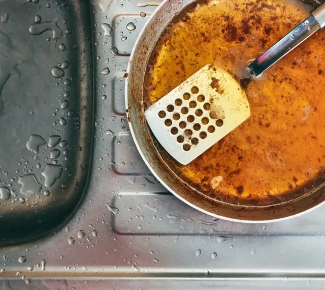 Zlepek zużytego oleju gastronomicznego na patelni obok zlewu.