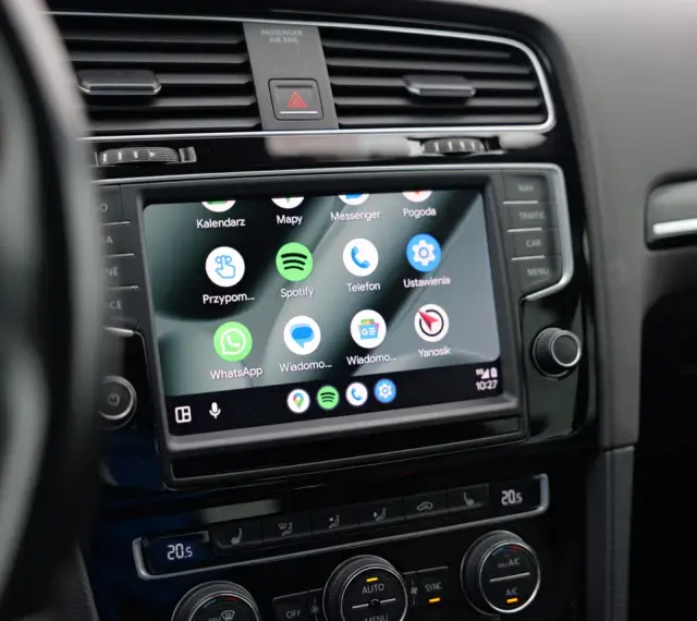 Ekran samochodu z widoczną aplikacją Android Auto, wyświetlającą ikony Kalendarz, Mapy, Spotify, WhatsApp i inne.