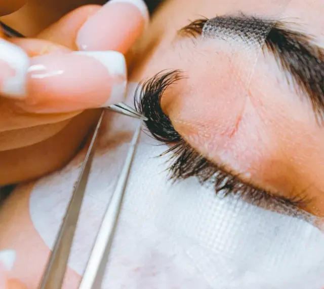 Precyzyjne przedłużanie rzęs: porównanie rzęsy 2d i 3d. Stylistka z perfekcyjnym manicurem dokłada kępki.