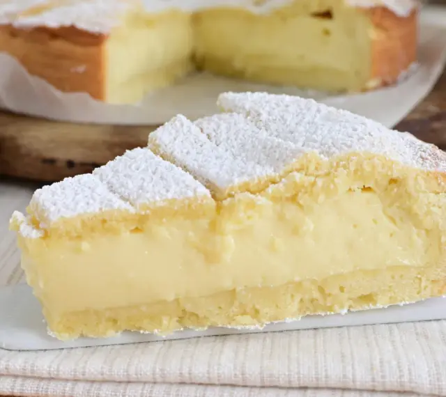 Fetta di crostata con abbondante crema allo yogurt, cosparsa di zucchero a velo.