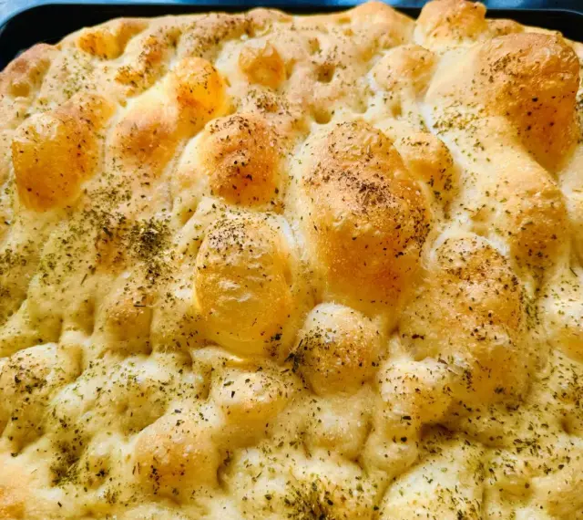 Chrupiąca pizza focaccia z ziołami, świeżo wyjęta z pieca. Idealna na przekąskę.