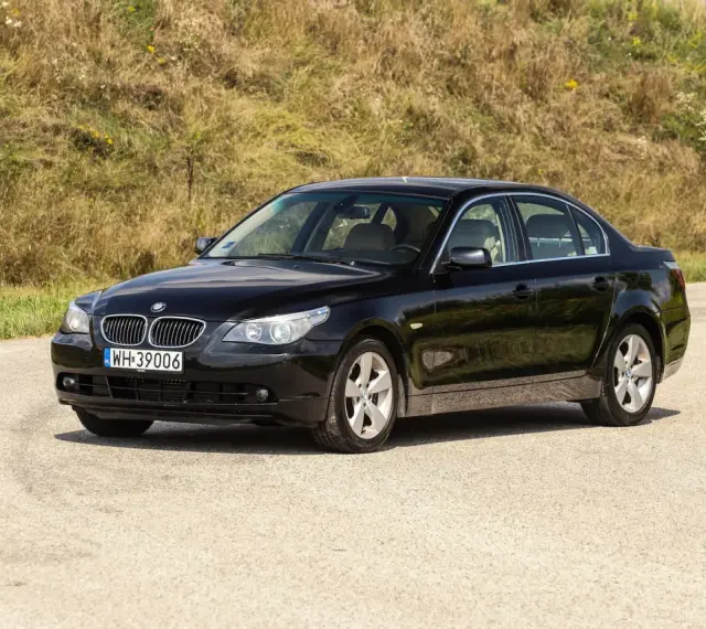 Czarne BMW 535d na tle zielonego wzgórza.