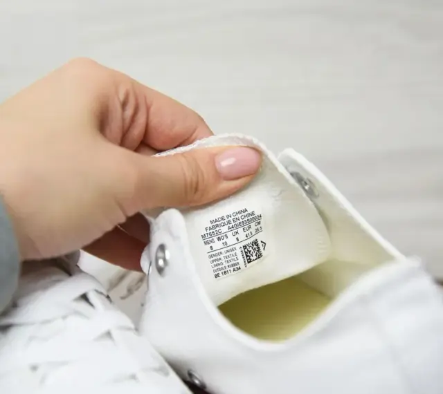 Porównanie converse oryginalne a podróbki. Dłoń pokazuje metkę z rozmiarem na białym bucie.