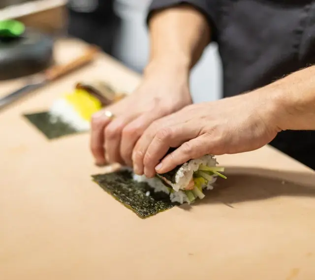 Ręce zwijają sushi na nori. Zastanawiasz się, nori gdzie kupić? W sklepach z azjatycką żywnością lub online.