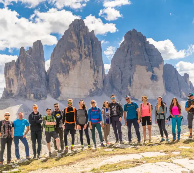 Grupa przyjaciół na tle Tre Cime di Lavaredo podczas niezapomnianego trekkingu w Dolomitach.