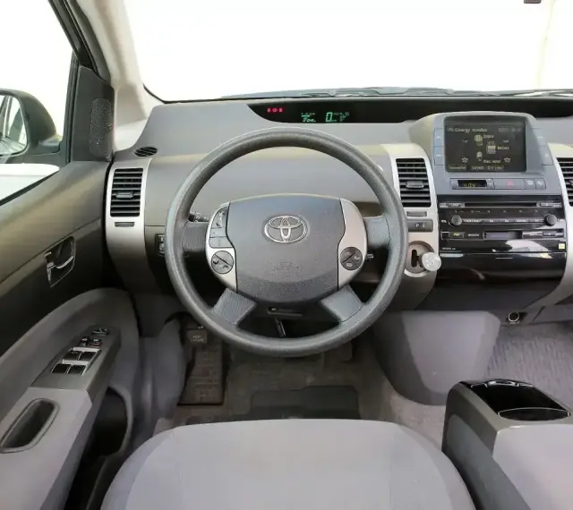 Wnętrze Toyoty Prius 2 z kierownicą, panelem radia i ekranem.