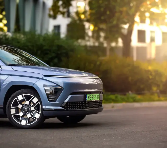Niebieski Hyundai Kona Electric zaparkowany na ulicy, z widocznym przodem i kołem.