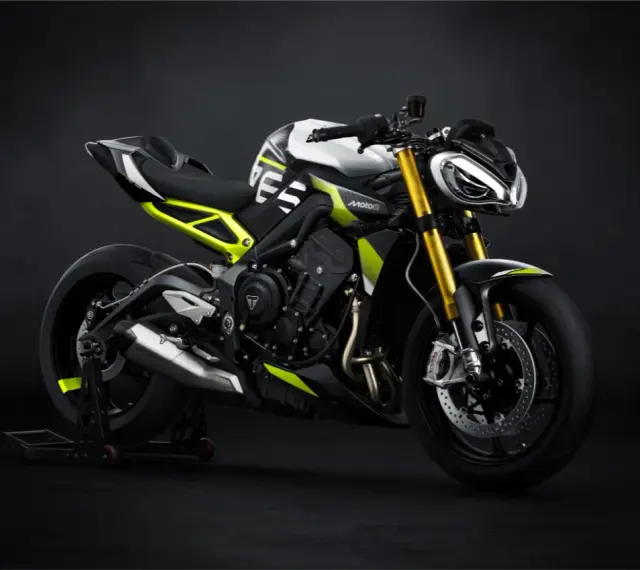 Agresywny Triumph Street Triple w biało-czarnej kolorystyce z neonowo-żółtymi akcentami, zdominowany przez złote lagi i sportowy wygląd.